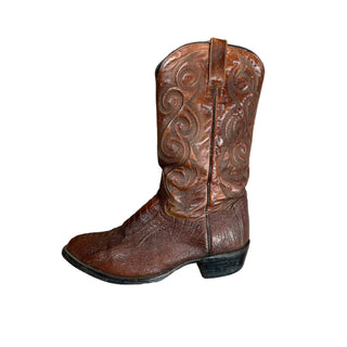 Brown leather boot with intricate designs on a wooden surface