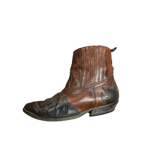 Brown leather cowboy boot on a wooden floor