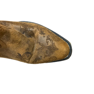 Brown leather shoe with intricate design on a wooden floor