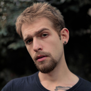 Man with a beard and tattoo on his neck against a blurred natural background
