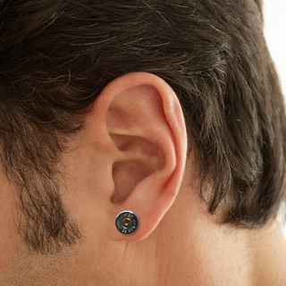 Close-up of a person's ear wearing a small round earring.