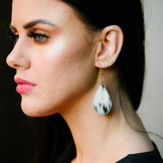 Close-up of a woman wearing a silver teardrop earring with a blurred background
