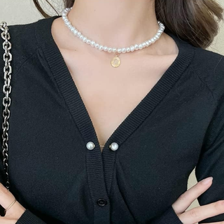 Person wearing a black cardigan with pearl buttons and a pearl necklace.