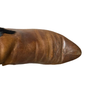 Brown leather boot on a white floor