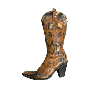 Brown cowboy boot with intricate designs on a wooden surface