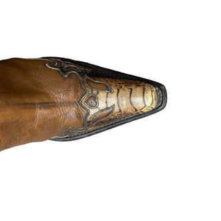 Close-up of a brown leather boot with decorative sole on a white floor.