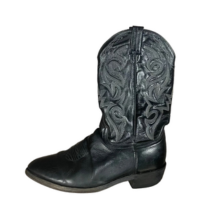 Black cowboy boot with intricate designs on a wooden floor