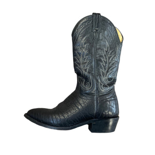 A black cowboy boot with detailed stitching and a yellow flower on the toe, displayed at Four Elks