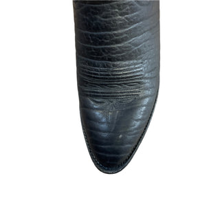 A black cowboy boot with detailed stitching and a yellow flower on the toe, displayed at Four Elks