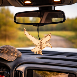 Decorative car air freshener shaped like a bird hanging from a car's rearview mirror with a blurred outdoor background.