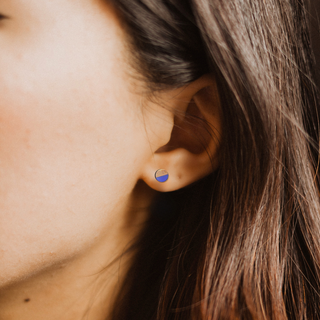 Close-up of an ear wearing a blue earring with a blurred background