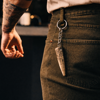 Person wearing brown pants with a keychain featuring a stone pendant.