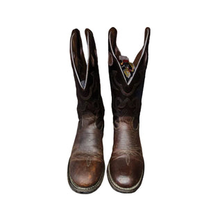 Pair of brown cowboy boots on a wooden floor with a white background.