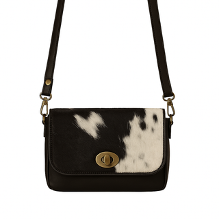 Black and white cowhide leather crossbody bag with gold clasp on a white background