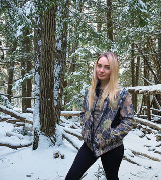 Woman in a patterned jacket standing in a snowy forest
