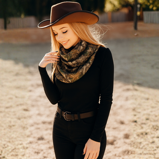 Woman wearing a brown cowboy hat and camouflage scarf in an outdoor setting