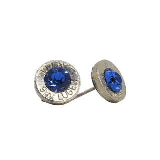A pair of stud earrings made from recycled bullet casing with an sapphire gemstone, set against a white background.