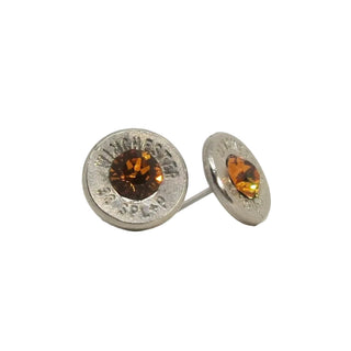 A pair of stud earrings made from recycled bullet casing with an topaz gemstone, set against a white background.